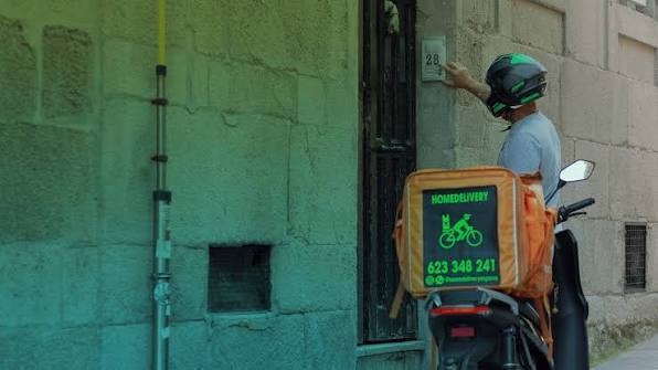 Rider de HomeDelivery llamando a un portal de Vigo con la caja de reparto en la moto