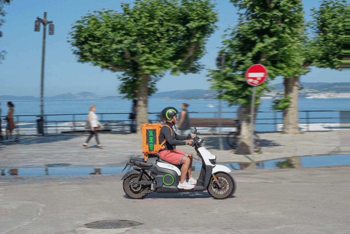 Rider de HomeDelivery en moto eléctrica por el paseo marítimo de Vigo