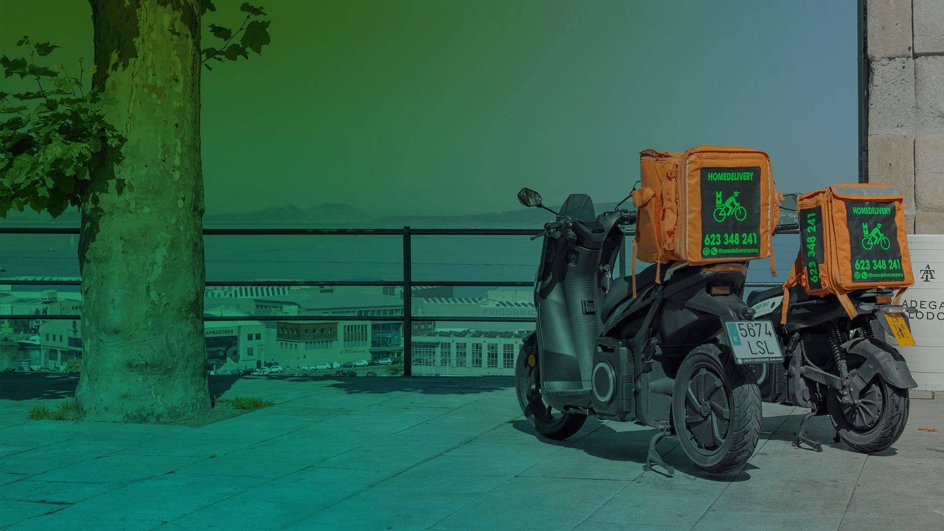 Motos eléctricas de HomeDelivery con cajas de reparto naranjas aparcadas frente a la ría de Vigo